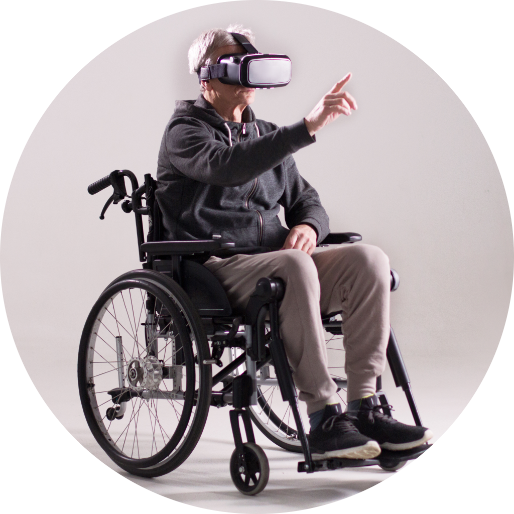 A man sitting in a wheelchair, wearing VR glasses, appears to be engaged in a virtual reality experience